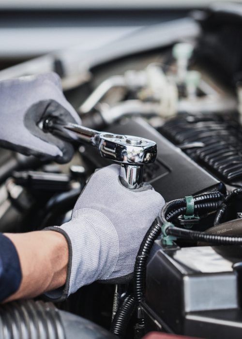 Professional mechanic working on the engine of the car in the garage. Car repair service.